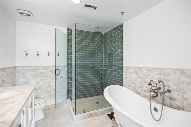 3235 Roswell Rd NE Unit 521, Atlanta, GA 30305 - bathroom featuring tile walls, a wainscoted wall, a shower stall, a soaking tub, and vanity