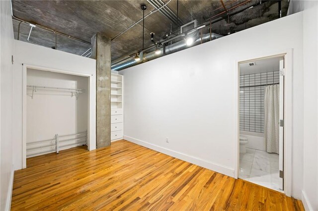 3235 Roswell Rd NE Unit 521, Atlanta, GA 30305 - unfurnished bedroom with wood finished floors, a closet, ensuite bath, rail lighting, and baseboards
