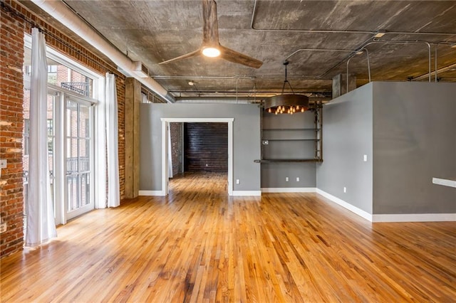 3235 Roswell Rd NE Unit 521, Atlanta, GA 30305 - spare room with hardwood / wood-style flooring, a chandelier, baseboards, a ceiling fan, and brick wall