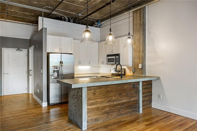 3235 Roswell Rd NE Unit 521, Atlanta, GA 30305 - kitchen with appliances with stainless steel finishes, a peninsula, white cabinetry, dark wood-style floors, and baseboards
