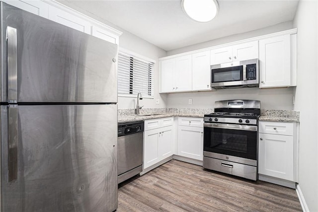 kitchen with white cabinetry, sink, stainless steel appliances, and light stone counters