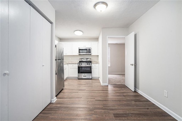 kitchen featuring white cabinetry, dark hardwood / wood-style flooring, stainless steel appliances, and a textured ceiling