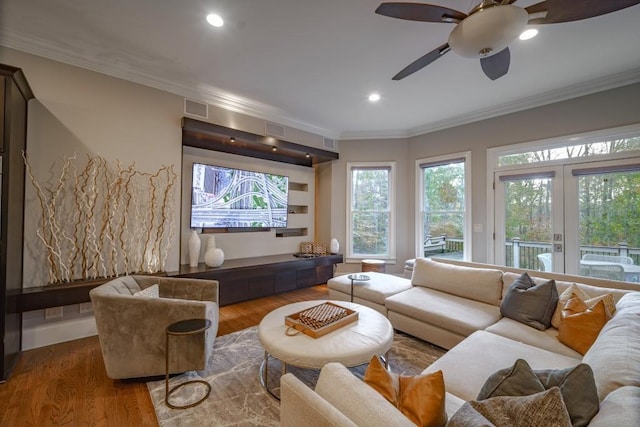 living area with visible vents, ornamental molding, and wood finished floors