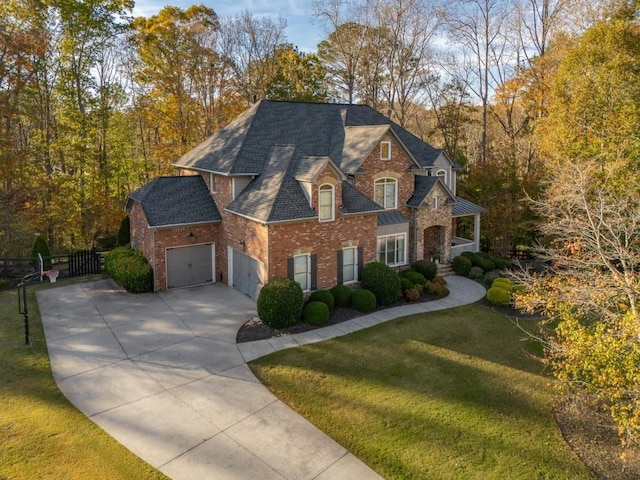 view of front of property featuring brick siding, a front lawn, fence, a garage, and driveway