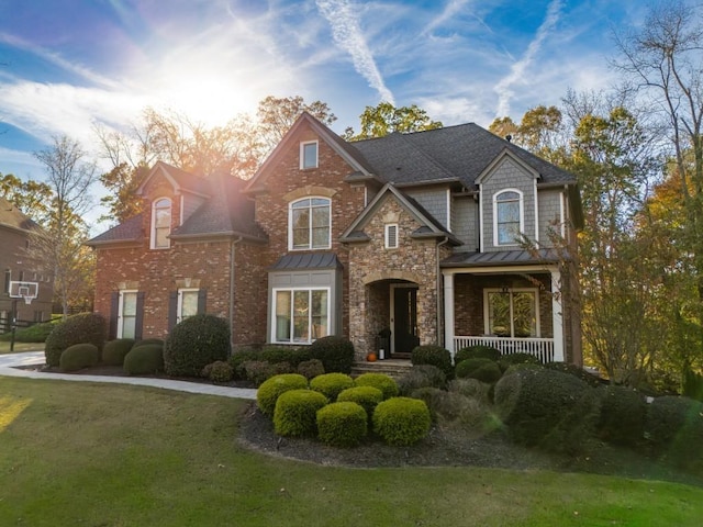 view of front of property with brick siding, covered porch, a standing seam roof, and a front yard