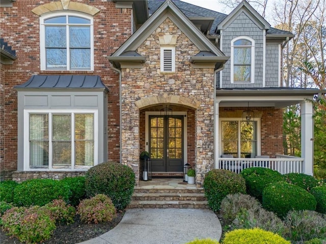 property entrance with brick siding, a porch, french doors, and stone siding