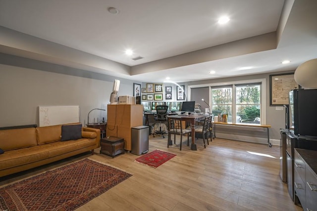 living room with visible vents, baseboards, recessed lighting, light wood-style floors, and a raised ceiling