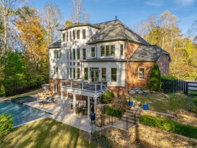 rear view of house featuring a patio, a yard, a wooden deck, brick siding, and fence private yard