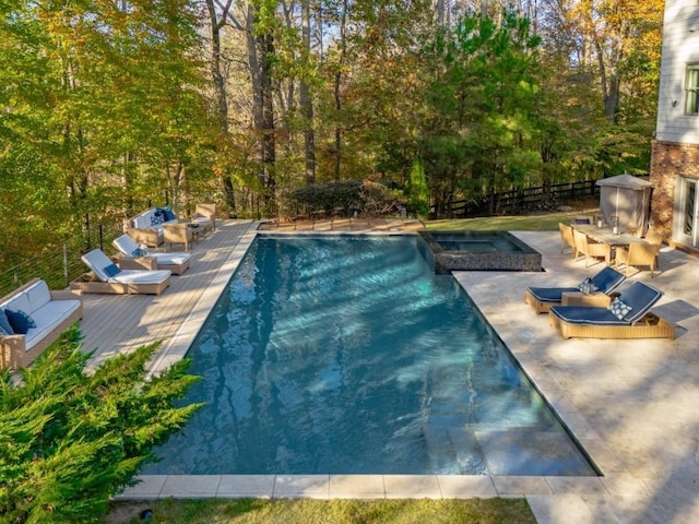 view of pool featuring a pool with connected hot tub, a deck, and fence