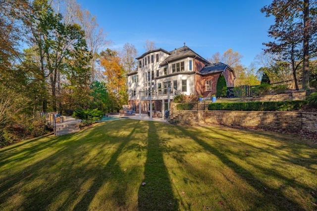 rear view of property featuring a patio, a lawn, and stairs