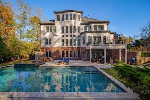 rear view of property featuring an outdoor pool, fence, a patio area, and brick siding