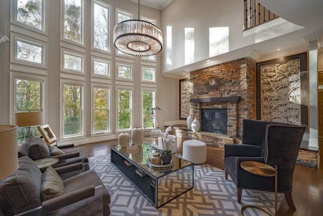 living room with a notable chandelier, ornamental molding, a fireplace, and wood finished floors