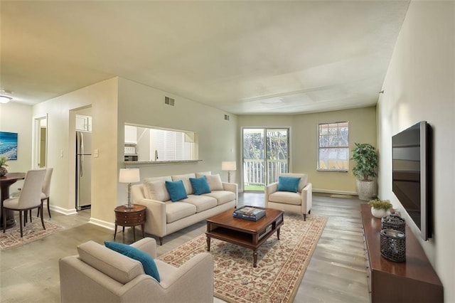 living room with visible vents, baseboards, and wood finished floors