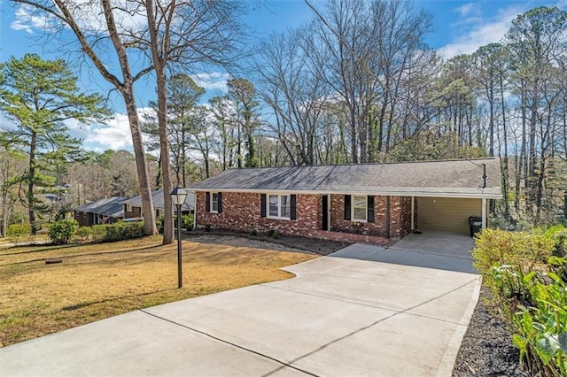 ranch-style home featuring brick siding, an attached carport, driveway, and a front yard