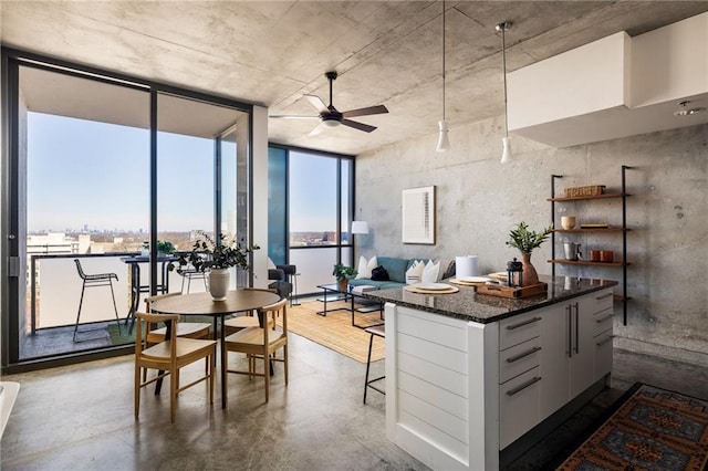 dining space with concrete flooring, ceiling fan, and expansive windows