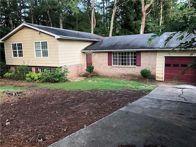 split level home featuring a garage, brick siding, and driveway