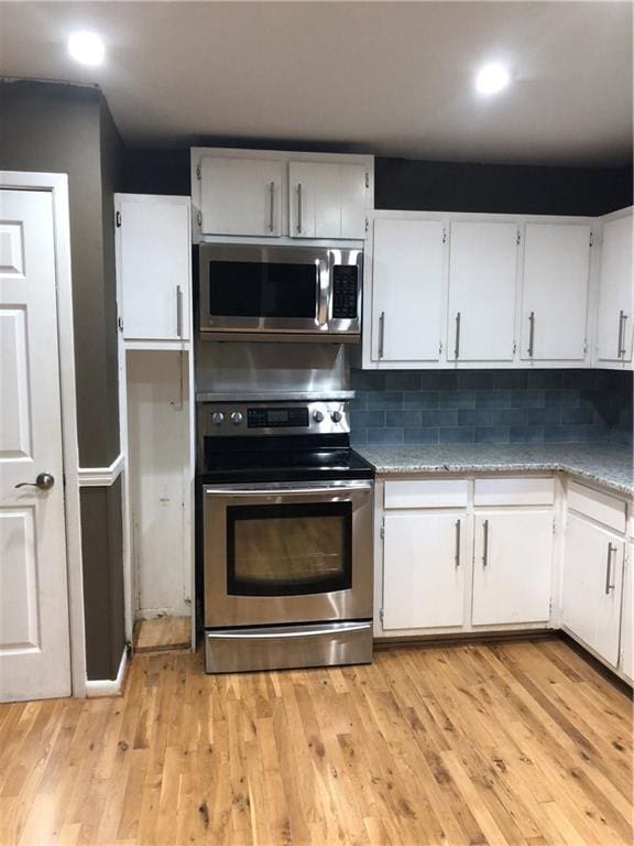 kitchen featuring stainless steel appliances, backsplash, light wood-style flooring, and white cabinets