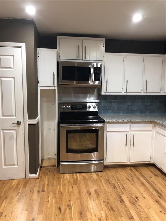 kitchen with tasteful backsplash, light wood-style flooring, white cabinetry, and stainless steel appliances