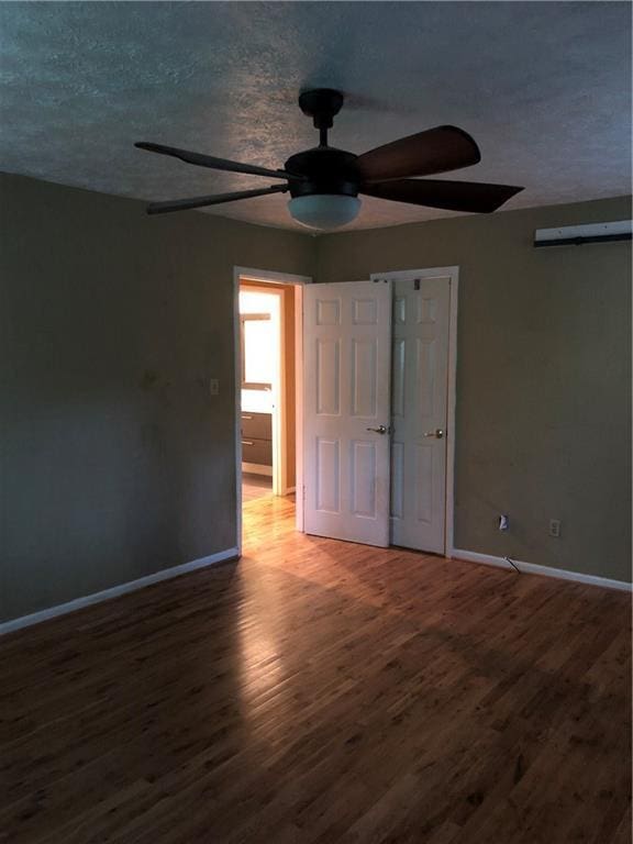 unfurnished bedroom featuring wood finished floors, baseboards, and a textured ceiling