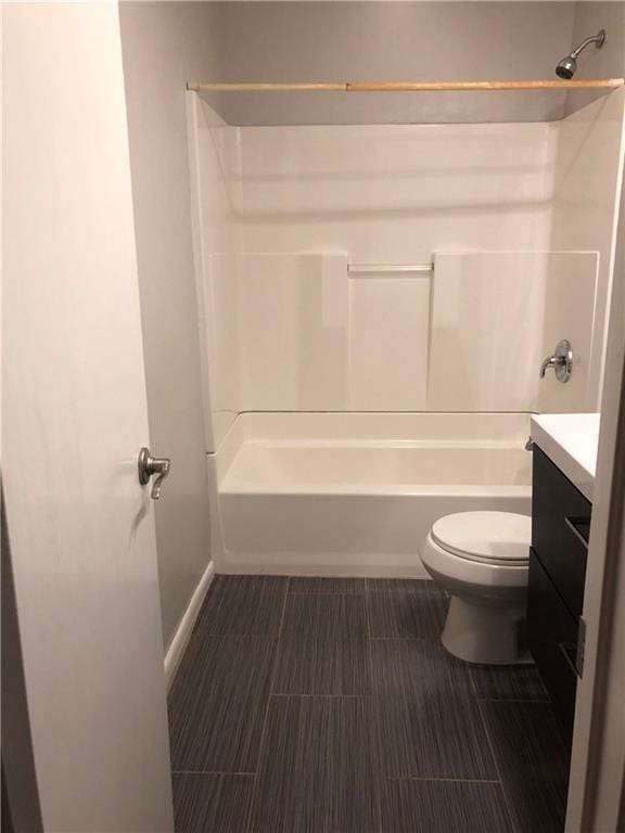 bathroom with tub / shower combination, baseboards, toilet, and vanity