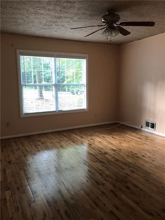 unfurnished room featuring visible vents, baseboards, hardwood / wood-style flooring, a textured ceiling, and a ceiling fan