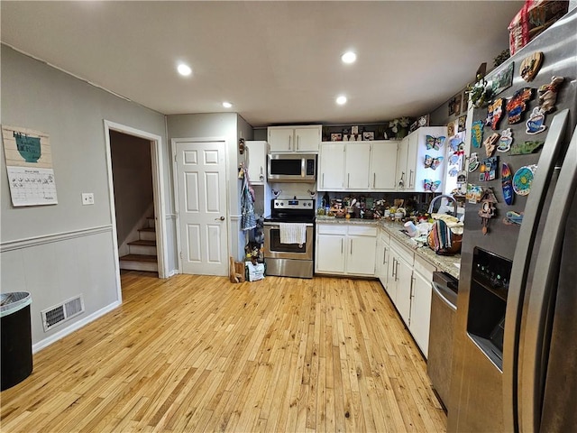 kitchen with visible vents, light countertops, light wood-style flooring, stainless steel appliances, and white cabinetry