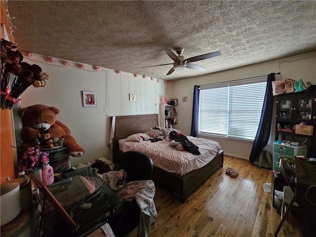 bedroom with a textured ceiling, ceiling fan, and wood-type flooring