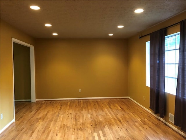 empty room with light wood finished floors, recessed lighting, and baseboards