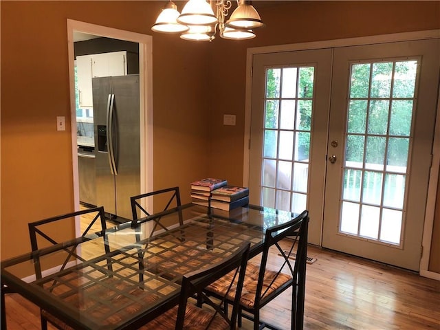 dining room featuring french doors, light wood-style floors, and a chandelier