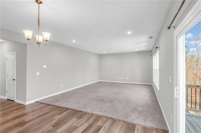 empty room with hardwood / wood-style floors and a notable chandelier