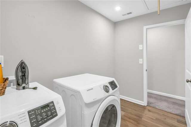 clothes washing area with light hardwood / wood-style floors and washer and clothes dryer