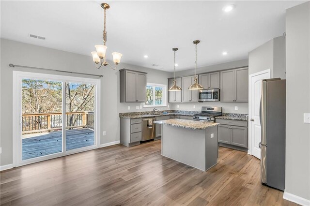 kitchen featuring gray cabinets, a kitchen island, pendant lighting, and appliances with stainless steel finishes