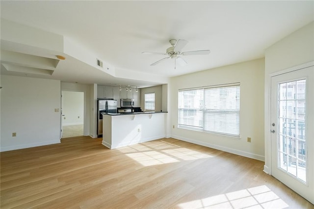 kitchen with ceiling fan, stainless steel appliances, kitchen peninsula, and light hardwood / wood-style flooring