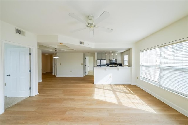 unfurnished living room with light hardwood / wood-style flooring and ceiling fan