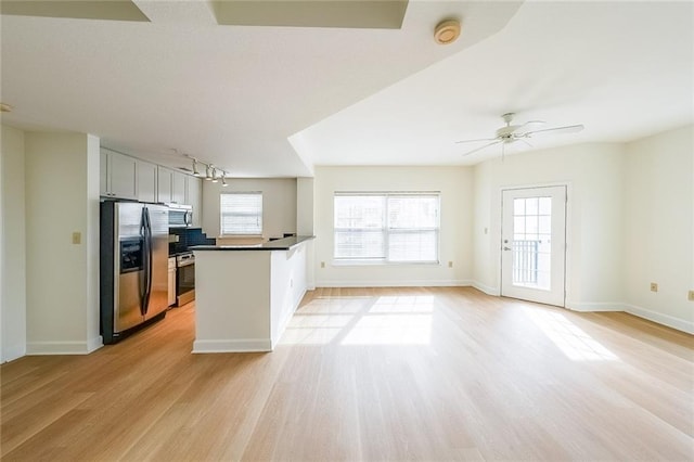 kitchen featuring appliances with stainless steel finishes, kitchen peninsula, ceiling fan, and light hardwood / wood-style flooring