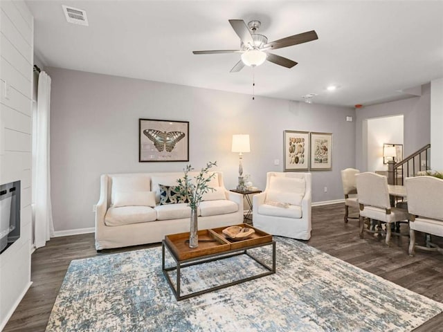 living room with ceiling fan, a fireplace, and dark hardwood / wood-style flooring