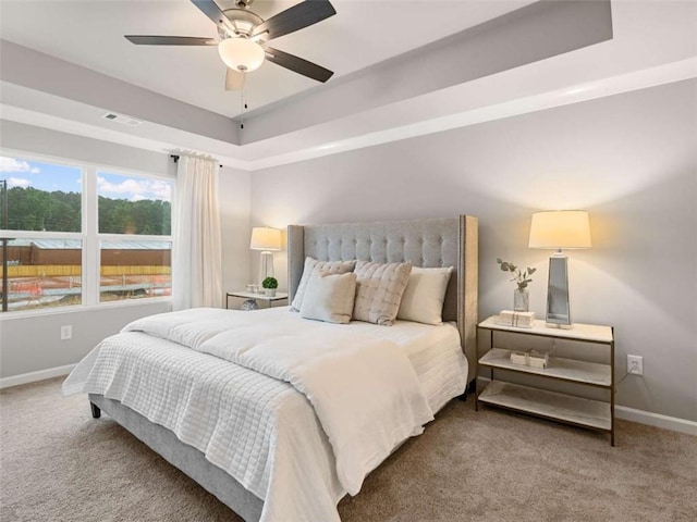 carpeted bedroom featuring a raised ceiling and ceiling fan