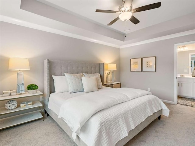 carpeted bedroom featuring connected bathroom, ceiling fan, and a tray ceiling