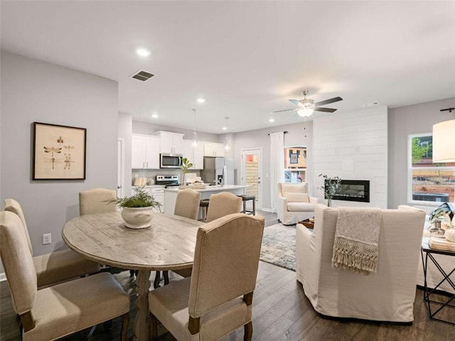 dining space featuring ceiling fan, a fireplace, and dark hardwood / wood-style floors