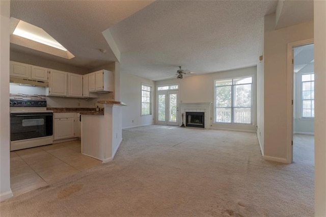 1015 Mcgill Park Ave NE, Atlanta, GA 30312 - kitchen featuring range with electric cooktop, under cabinet range hood, light colored carpet, a ceiling fan, and white cabinets