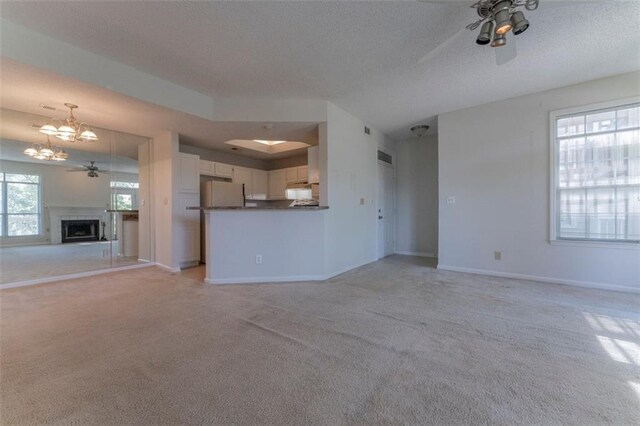 1015 Mcgill Park Ave NE, Atlanta, GA 30312 - unfurnished living room with light carpet, ceiling fan, a chandelier, a textured ceiling, and baseboards
