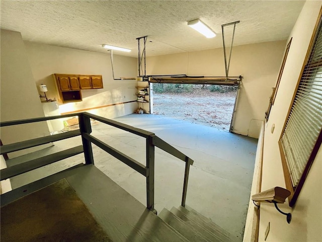 stairway with concrete floors and a textured ceiling