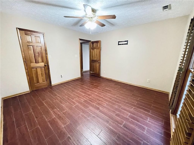 spare room featuring a textured ceiling, dark wood-type flooring, visible vents, and a ceiling fan