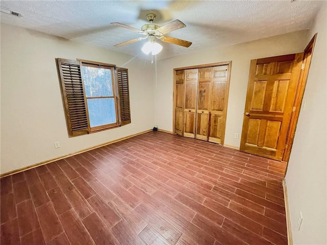 unfurnished bedroom featuring a closet, visible vents, ceiling fan, a textured ceiling, and wood finished floors