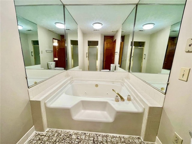 bathroom with a stall shower, baseboards, and a tub with jets