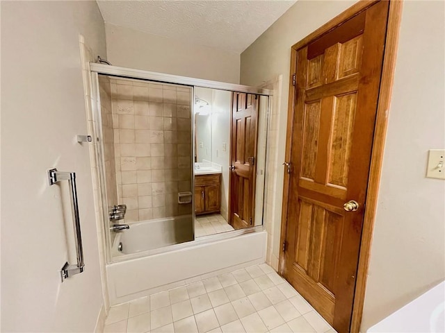 full bath featuring a textured ceiling, combined bath / shower with glass door, tile patterned flooring, and vanity