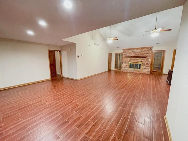 unfurnished living room with baseboards, a ceiling fan, wood finished floors, a brick fireplace, and high vaulted ceiling