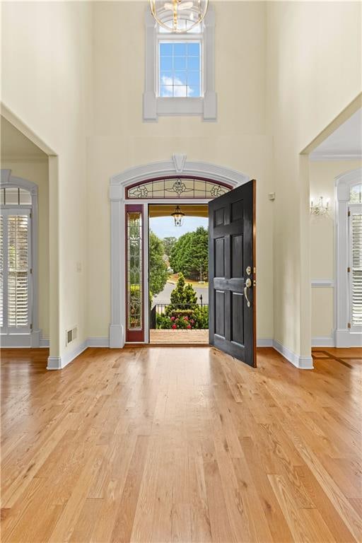 foyer entrance with a chandelier, hardwood / wood-style flooring, and a towering ceiling