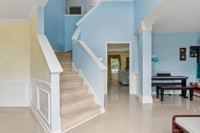 570 White Stag Ct, Suwanee, GA 30024 - stairs featuring wainscoting, tile patterned flooring, a decorative wall, crown molding, and ornate columns