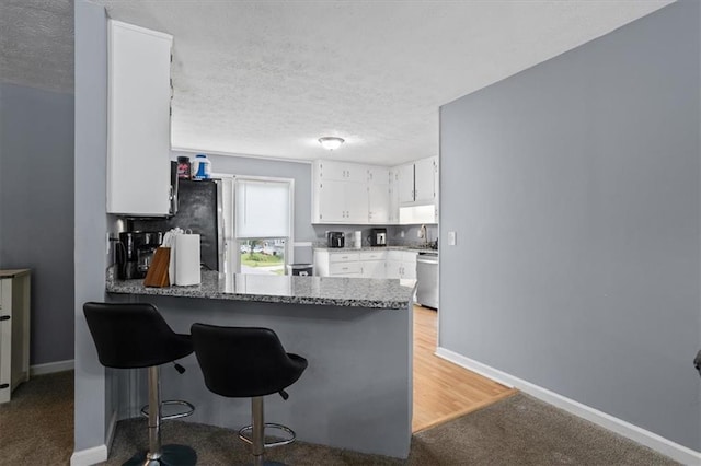 2711 Bluffton Rd, Buford, GA 30519 - kitchen featuring a peninsula, appliances with stainless steel finishes, light carpet, white cabinets, and a breakfast bar area